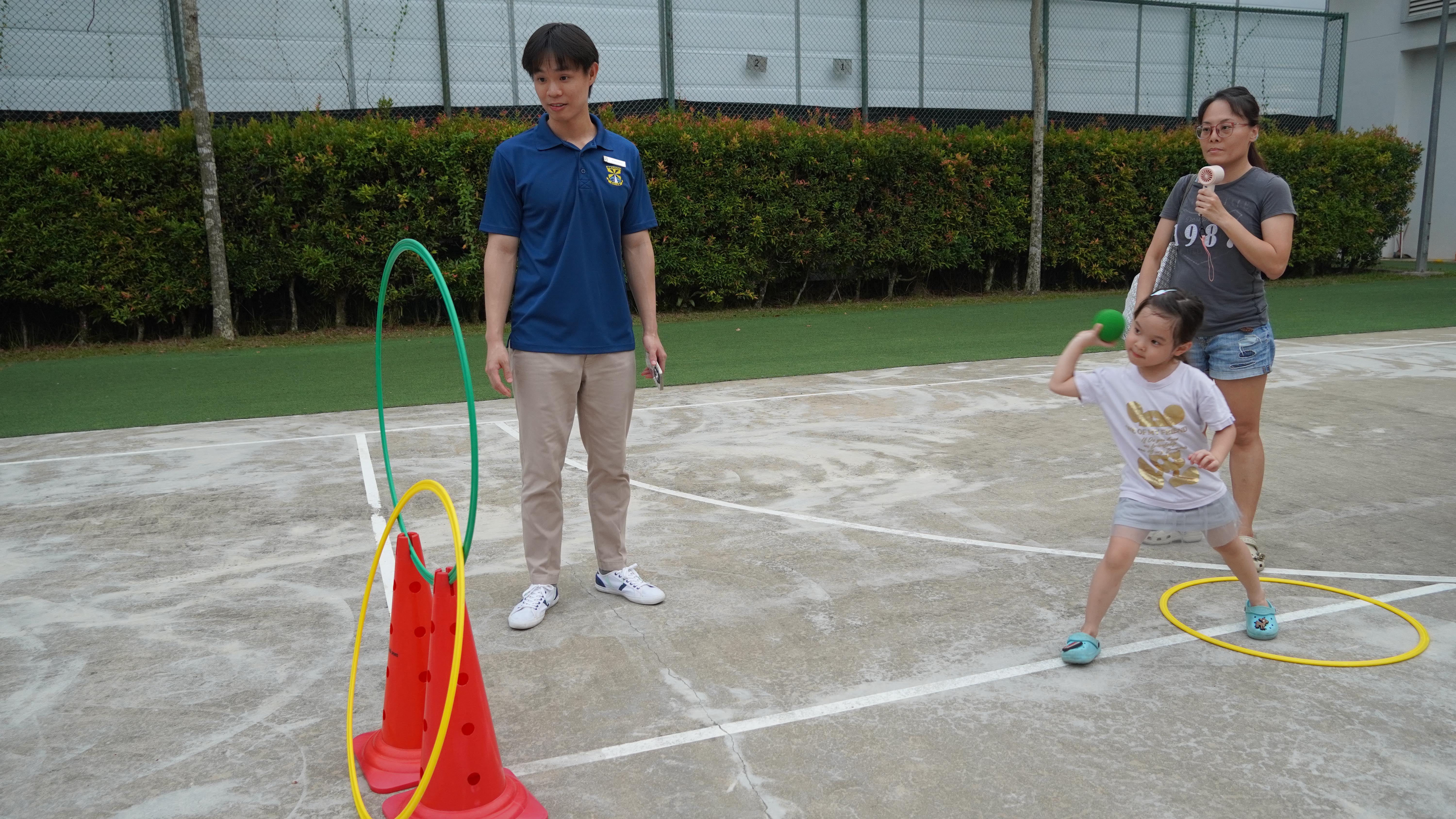 Eyes on the target! A young participant gives it her best shot while family members cheer her on.